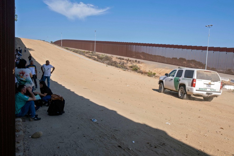 Patrulha de fronteira dos EUA passa por grupo de imigrantes que aguarda análise das autoridades americanas