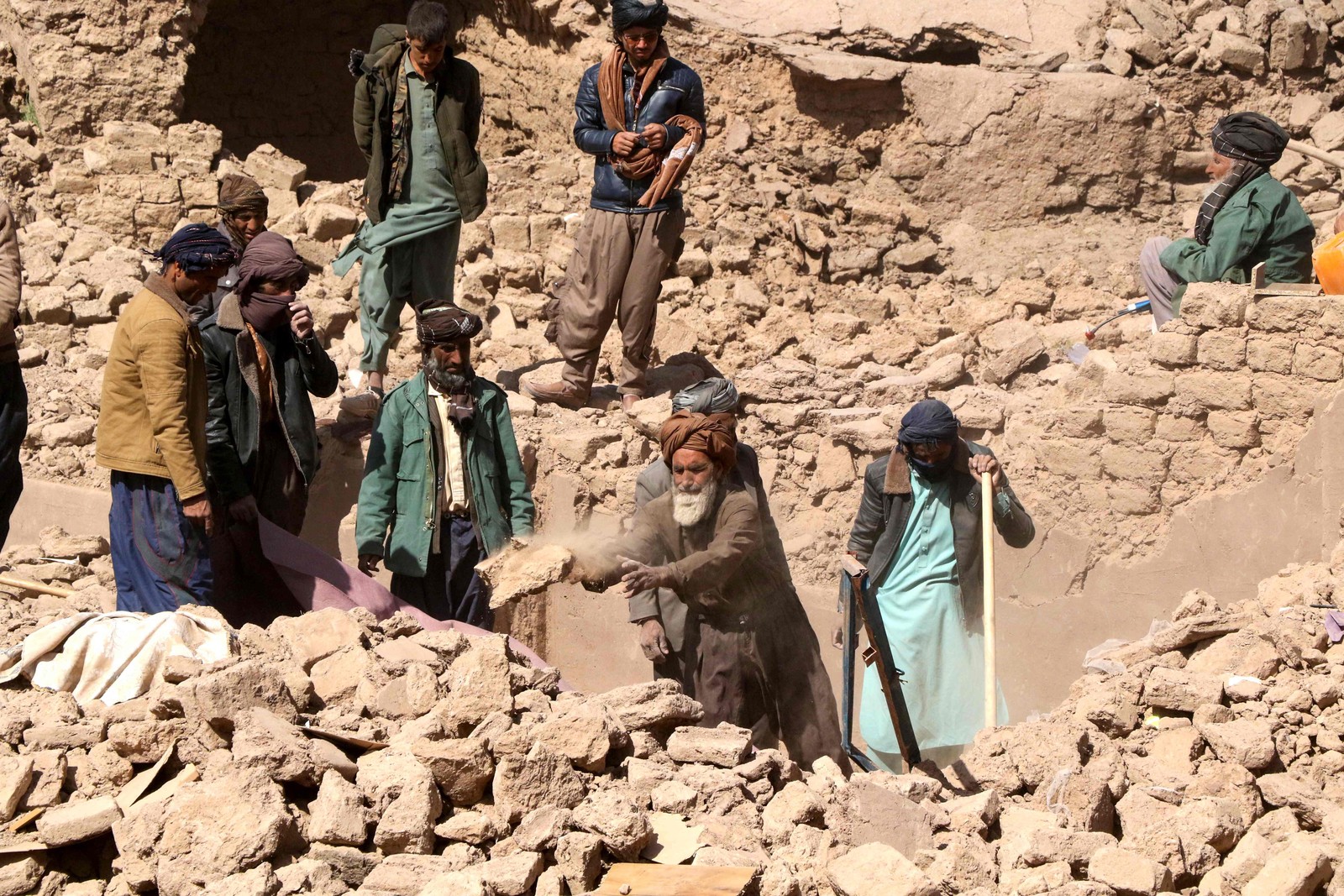 Moradores afeg&atilde;os limpam destro&ccedil;os enquanto procuram os corpos das v&iacute;timas nos escombros de casas danificadas ap&oacute;s os terremotos na prov&iacute;ncia de Herat &mdash; Foto: Mohsen KARIMI / AFP