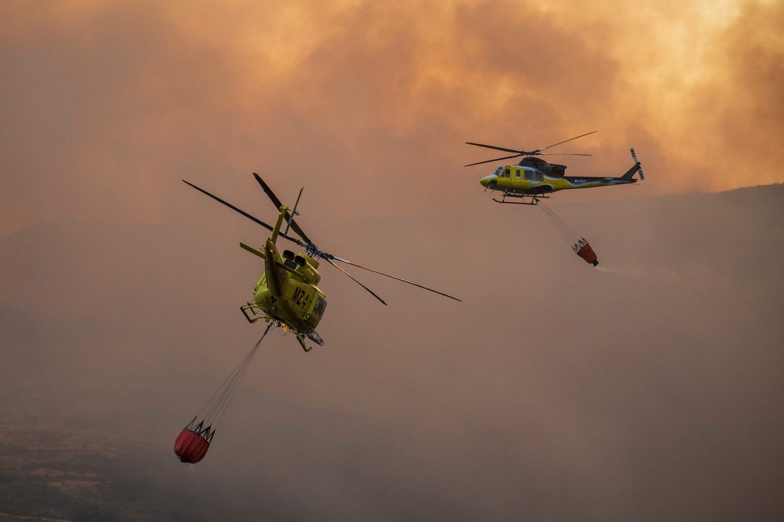 Helicópteros de bombeiros sobrevoam um incêndio florestal no Parque Natural da Baixa Limia, província de Ourense, noroeste da Espanha — Foto: MIGUEL RIOPA / AFP