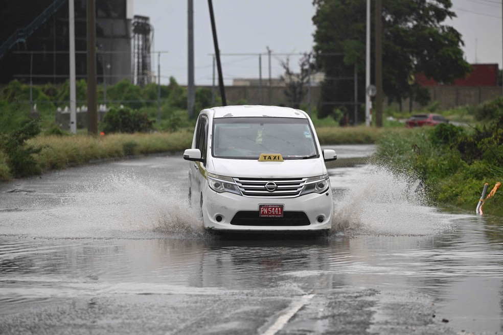 Carro passa por rua alagada em Kingston, na Jamaica: previsão é de até 1 metro de chuva — Foto: Ricardo Makyn/AFP