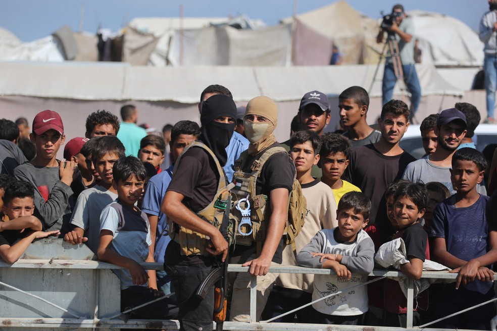 Combatente do Hamas controla multidão durante entrega de reféns a equipe da Cruz Vermelha — Foto: Bashar Taleb/AFP