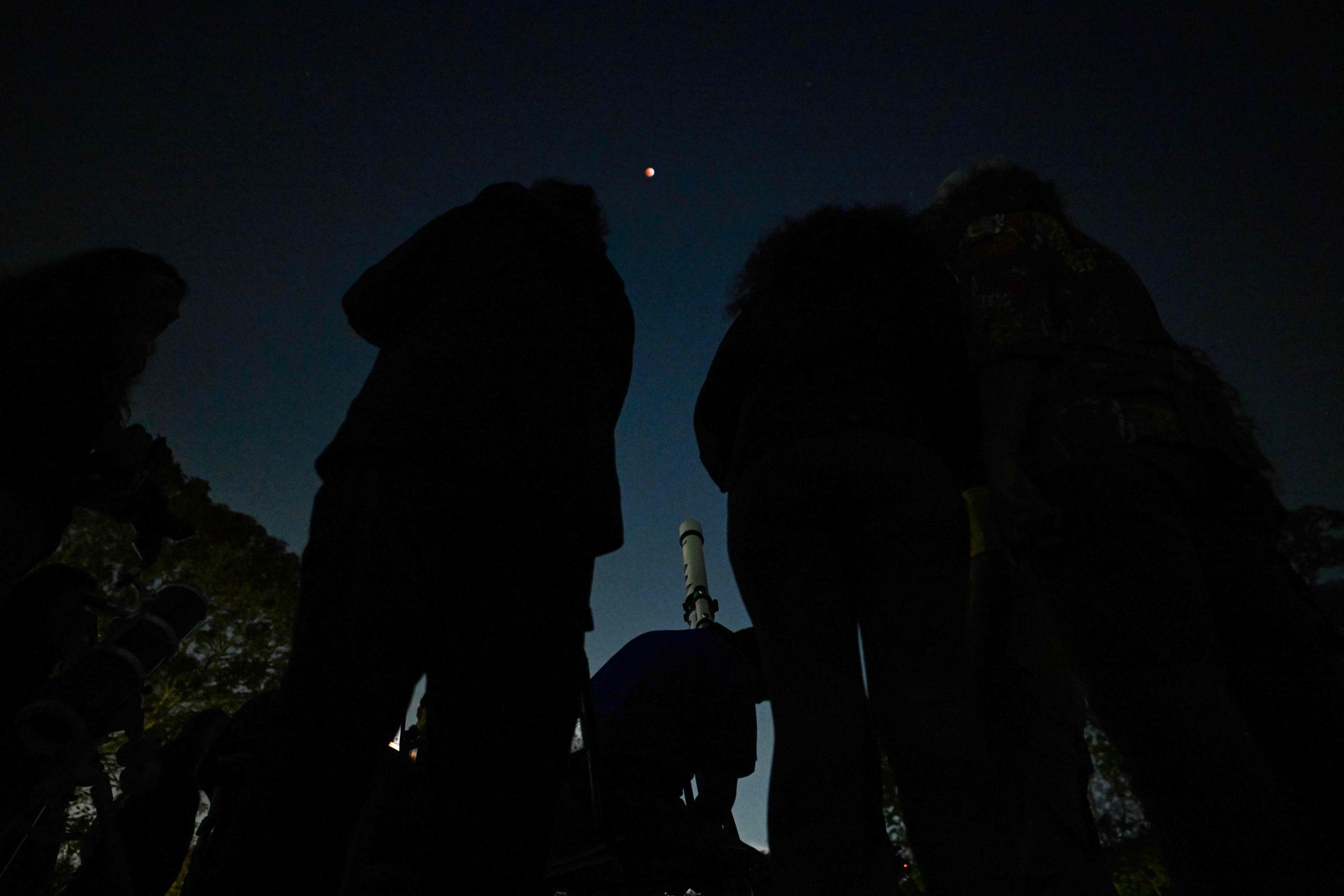 Pessoas observam lua de sangue em Caracas, EM 14 de Marçode2025 - Foto: Juan Barreto / AFP