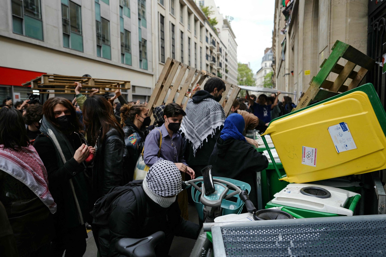 Manifestantes barricam a entrada do Instituto de Estudos Políticos (Sciences Po Paris) com caixotes e paletes de madeira enquanto participam numa manifestação em frente ao edifício ocupado por estudantes, em apoio aos palestinianos, em Paris — Foto: Dimitar DILKOFF / AFP