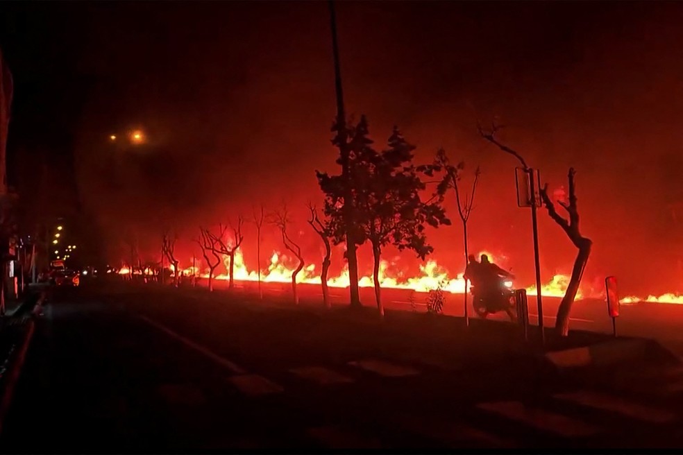 Esta imagem de vídeo retirada de imagens UGC publicadas nas redes sociais em 7 e 8 de março de 2026 mostra um incêndio a deflagrar num depósito de petróleo na capital do Irã, Teerã — Foto: UGC / AFP