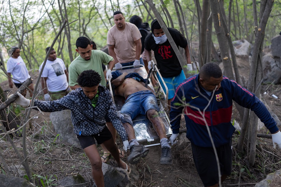 A remoção dos corpos foi feita também por adolescentes, e crianças chegaram a ajudar nas buscas — Foto: Eduardo Anizelli/Folhapress