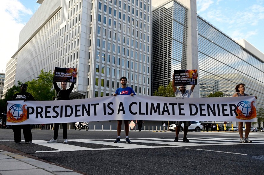 Ativistas exibem uma faixa chamando o presidente do Banco Mundial, David Malpass, de 'negacionista do clima', em frente à sede do Banco Mundial em Washington