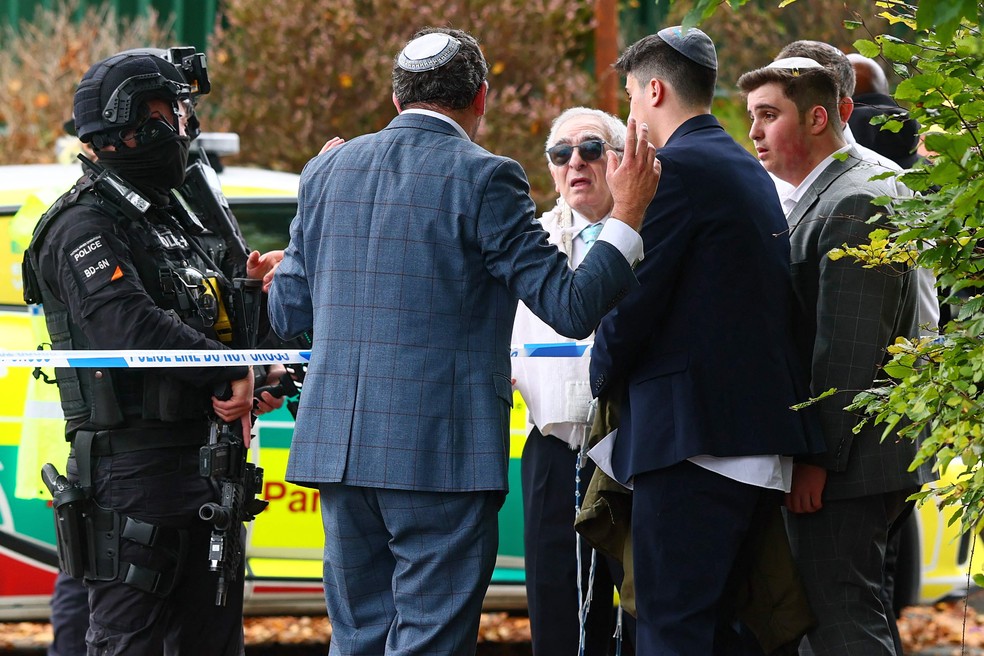 Policiais armados conversam com membros da comunidade judaica perto da sinagoga da Congregação Hebraica de Heaton Park, após ataque a faca — Foto: Paul Currie/AFP