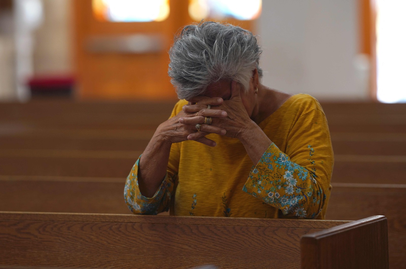 Mulher reza em homenagens às vítimas do ataque na Igreja Católica do Sagrado Coração, em Uvalde Texas — Foto: ALLISON DINNER / AFP