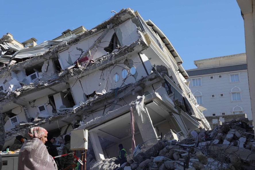 Mulher em frente aos destroços de um prédio destruído pelo terremoto, em Islahiye, Gaziantep