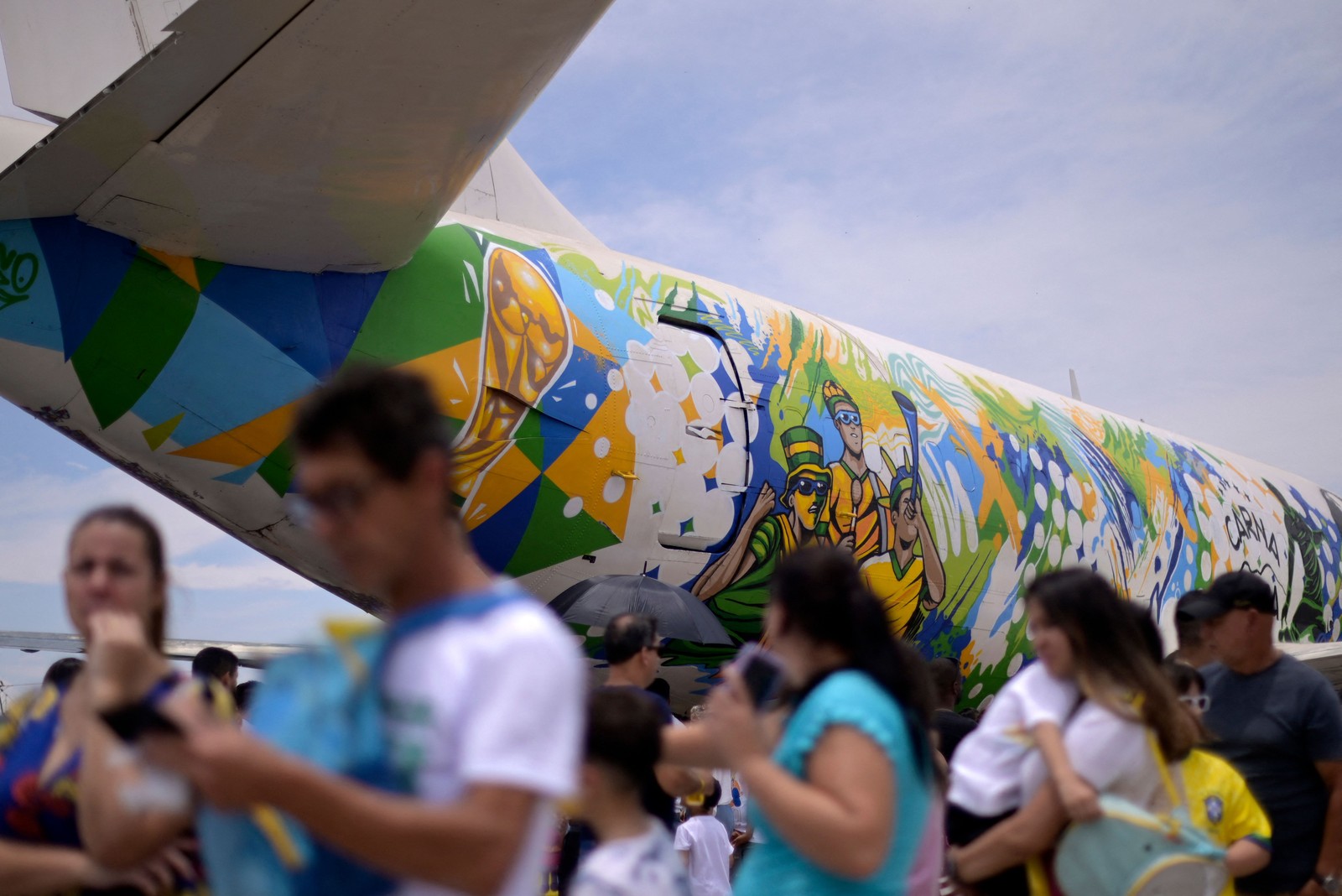 Fãs se reúnem para trocar adesivos de futebol da Copa do Mundo e colá-los na fuselagem de avião decorado em um shopping em Contagem, Minas Gerais. — Foto: DOUGLAS MAGNO / AFP