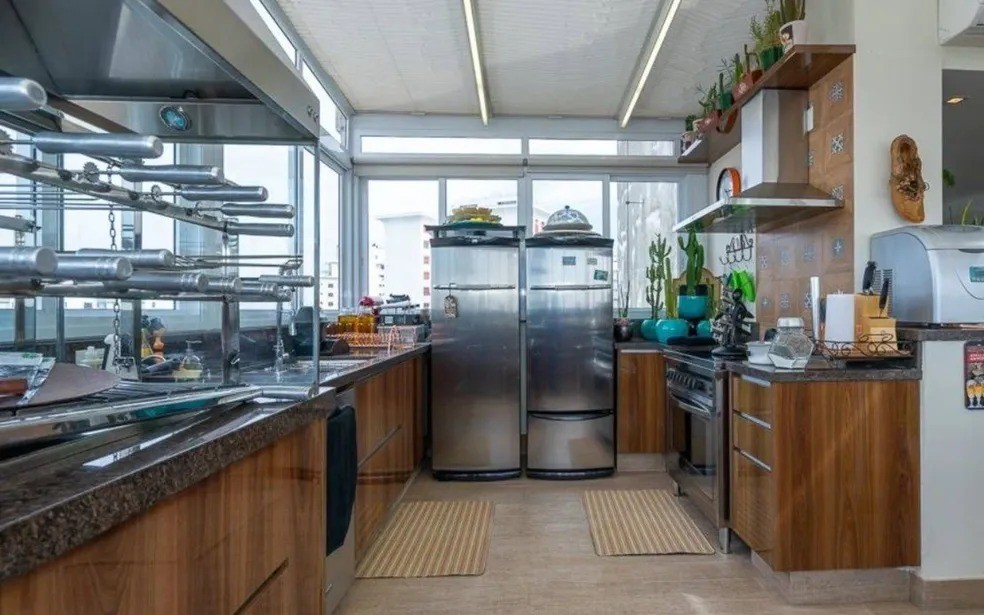 A cozinha do apartamento tem armários de madeira — Foto: Reprodução