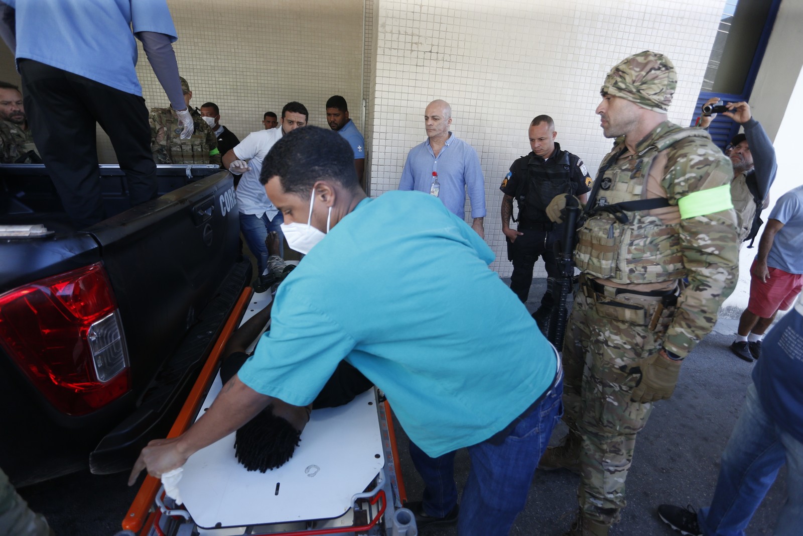 Baleado é levado pela polícia ao Hospital Getúlio Vargas, na Penha — Foto: Fabiano Rocha / Agência O Globo