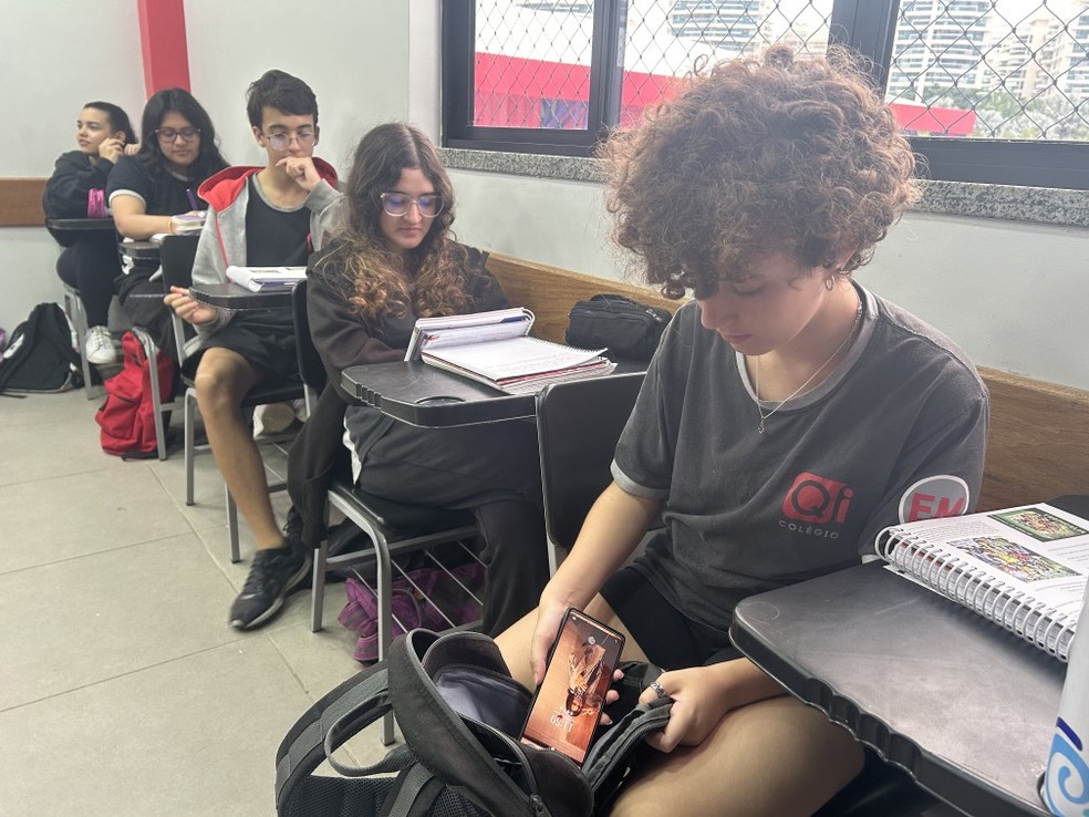 Aluna do Colégio Qi guarda o celular na mochila ao entrar em sala de aula — Foto: O Globo