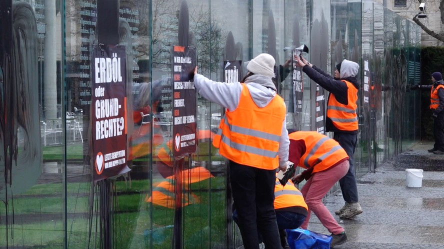 Ativistas climáticos borrifam líquido preto e colam cartazes em monumento onde estão gravados artigos da Constituição, em Berlim