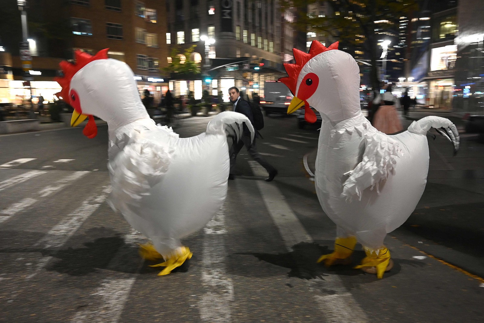 Duas pessoas vestidas com fantasias de frango tentam atravessar a rua Broadway na Times Square durante o Halloween em Nova York — Foto: TIMOTHY A. CLARY/AFP