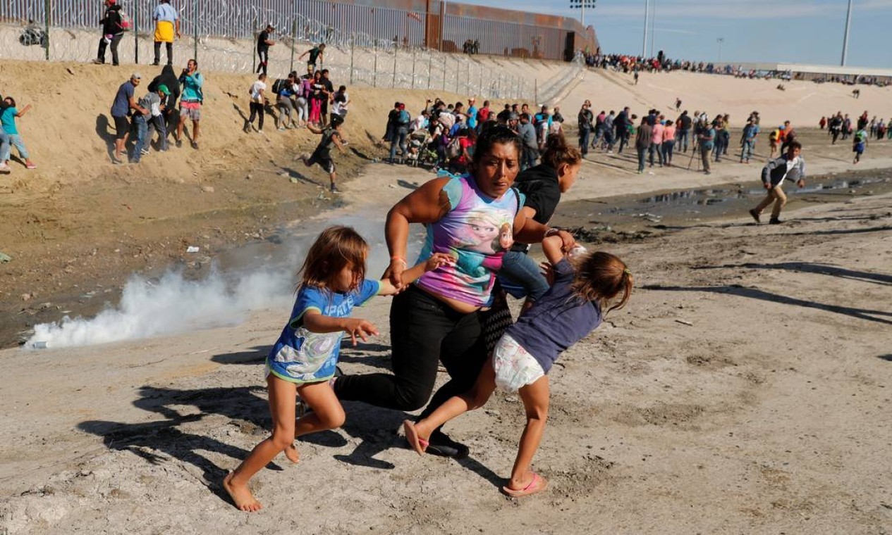Família de migrantes, parte de uma caravana de milhares de pessoas que viajam da América Central rumo aos Estados Unidos, fogem de gás lacrimogêneo na frente da fronteira entre os EUA e o México, em Tijuana, Cidade do México — Foto: KIM KYUNG-HOON / Reuters - 25/11/2018 