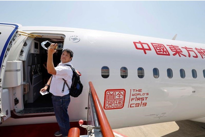Passageiro tira um self ao embarcar no primeiro jato de passageiros produzido na China, o C919  — Foto: AFP