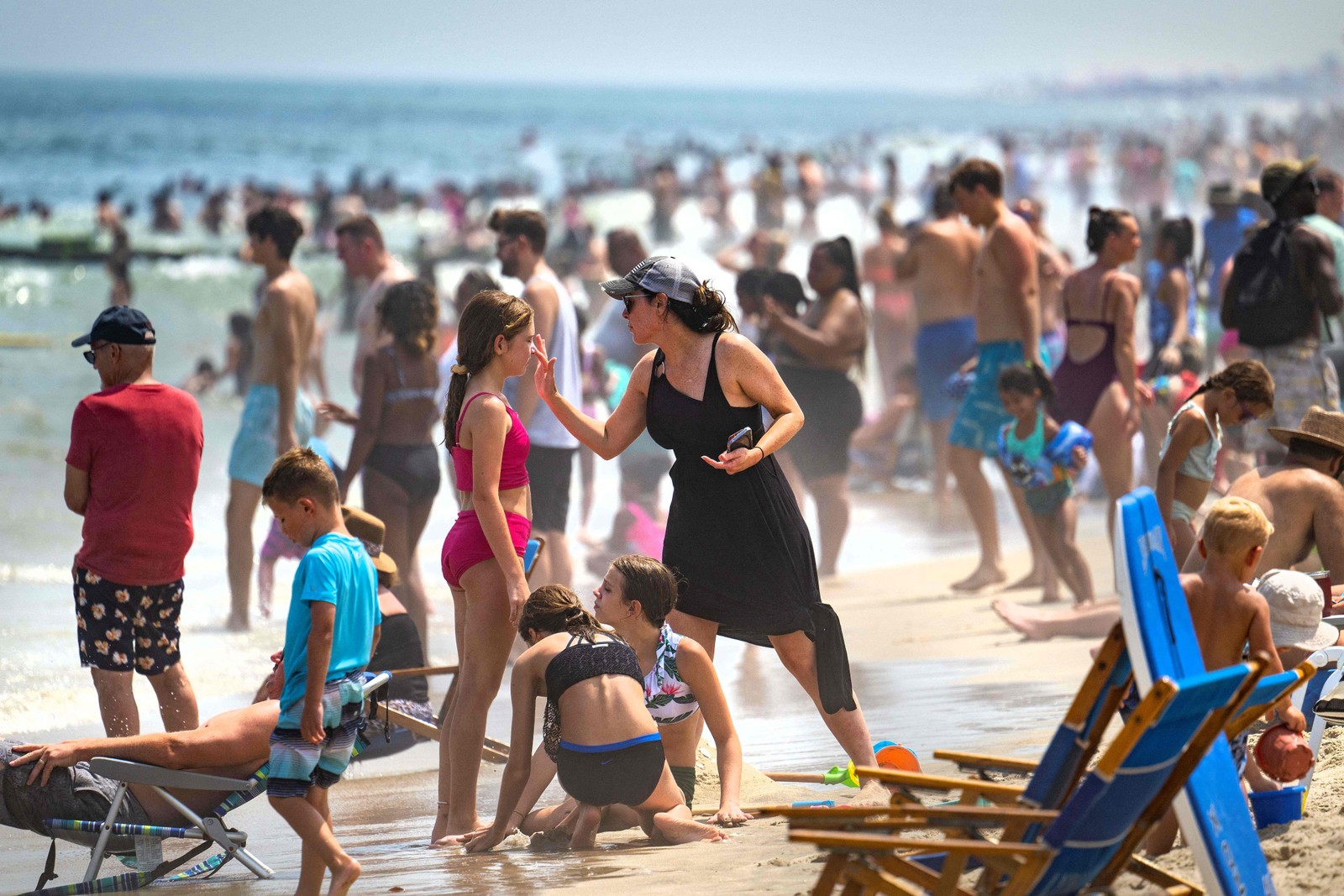 Mulher aplica protetor solar em uma menina em Rehoboth Beach — Foto: Jim WATSON / AFP