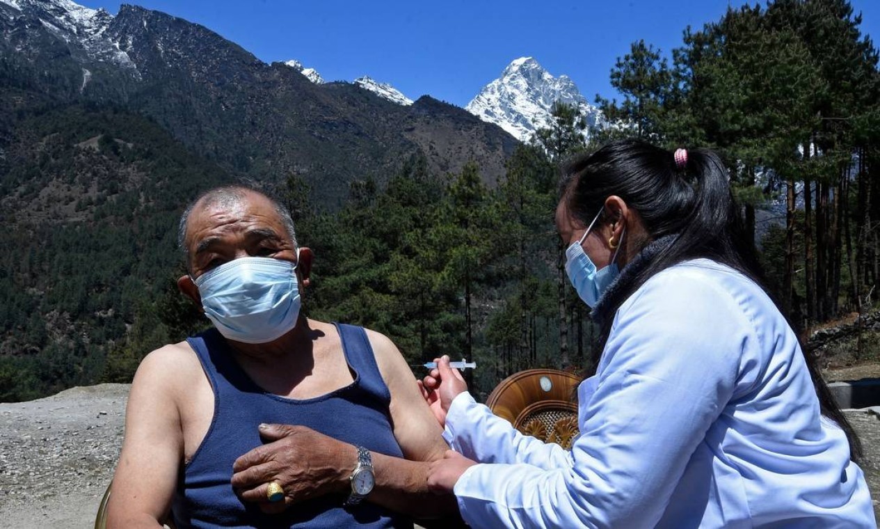 Um profissional de saúde inocula um homem com a dose da vacina Covishield contra o Covid-19 em um posto de saúde perto de Lukla, no nordeste do Nepal — Foto: PRAKASH MATHEMA / AFP