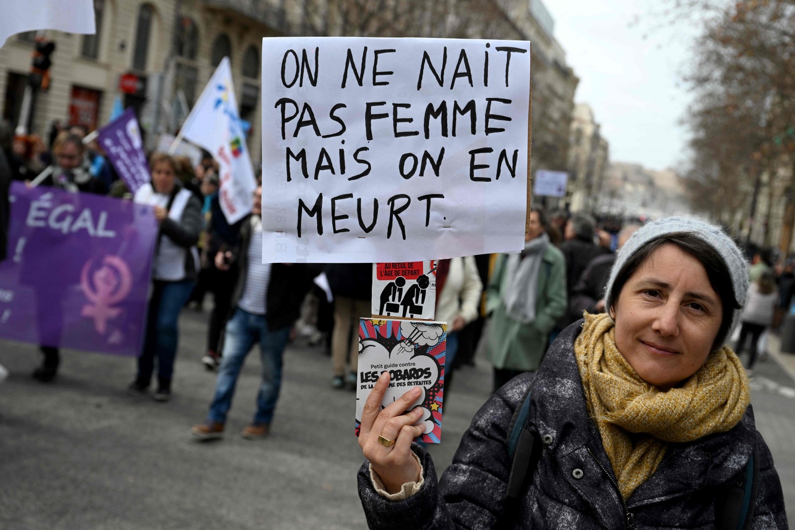 Manifestante segura cartaz que diz "Ninguém nasce mulher, mas morre sendo mulher" em marcha no Dia Internacional da Mulher, em 2023, em Marseille, na França. Nicolas Tucat / AFP