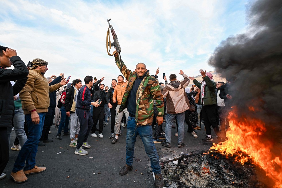 Pessoas comemoram na Praça Umayyad, em Damasco. Rebeldes tomaram a capital da Síria em uma ofensiva relâmpago em 8 de dezembro, fazendo com que o presidente Bashar al-Assad fugisse, encerrando cinco décadas de governo Baath no país — Foto: LOUAI BESHARA / AFP