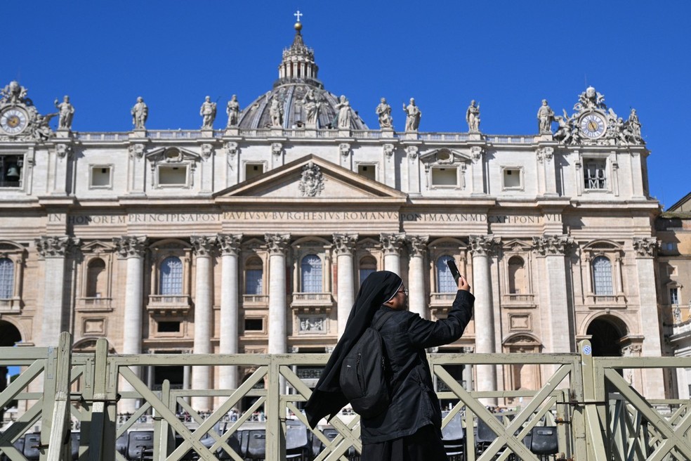 Freira tira fotos em frente à Basílica de São Pedro, no Vaticano — Foto: Andreas SOLARO / AFP