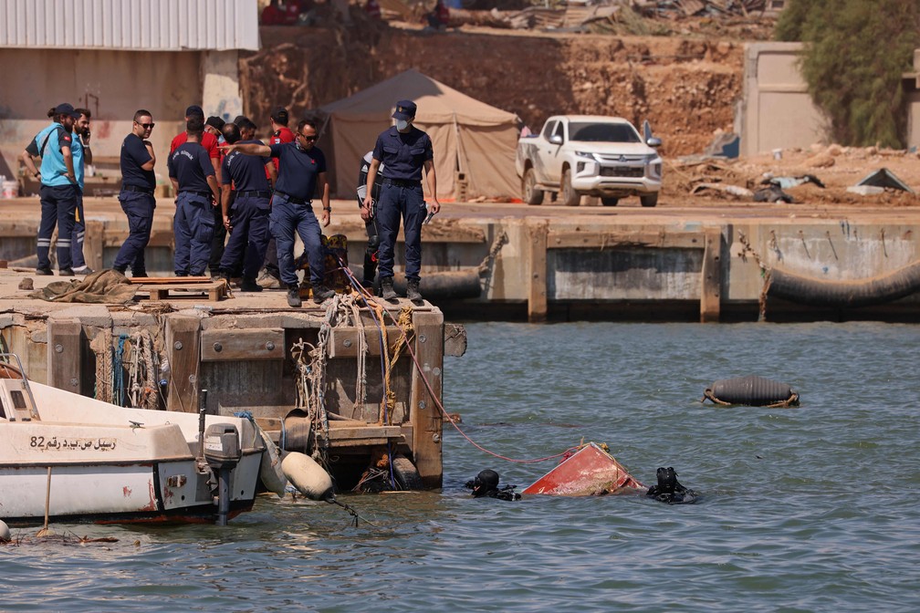 Membros da equipe de resgate russa mergulham no mar para resgatar corpos na cidade portuária de Derna, no leste da Líbia — Foto: KARIM SAHIB/AFP