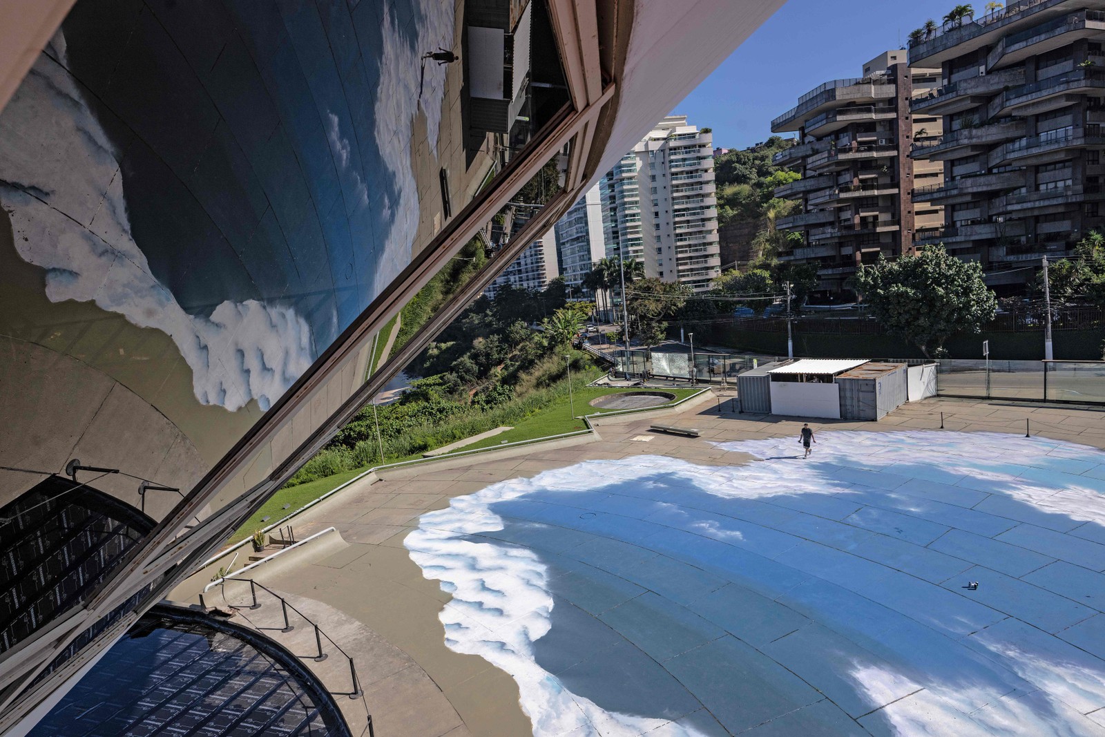 O grafiteiro brasileiro Toz pinta nuvens no chão do Museu de Arte Contemporânea, em Niterói — Foto: Carl de Souza/AFP