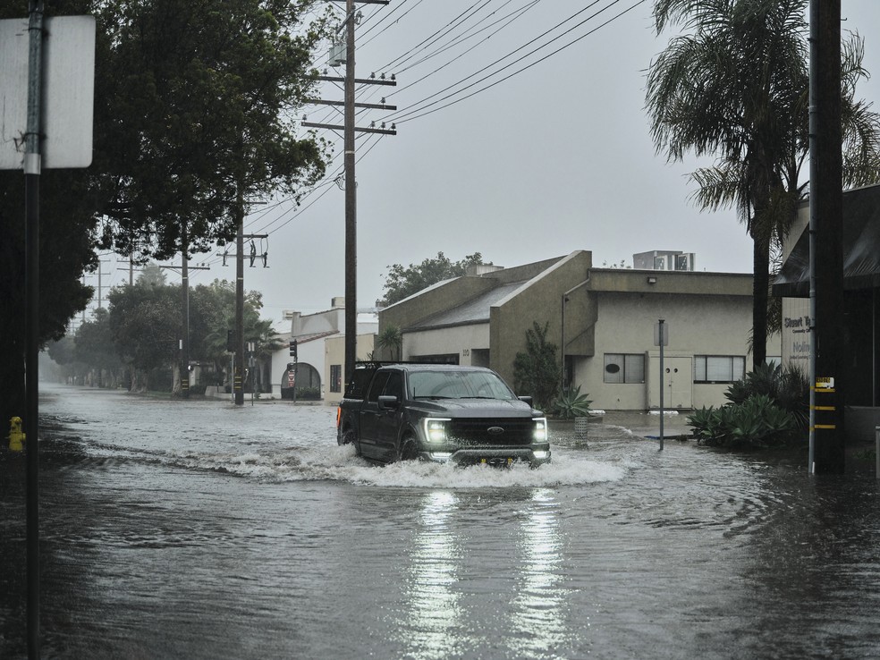 Carro tenta passar por área alagada em Santa Bárbara — Foto: Philip Cheung/The New York Times