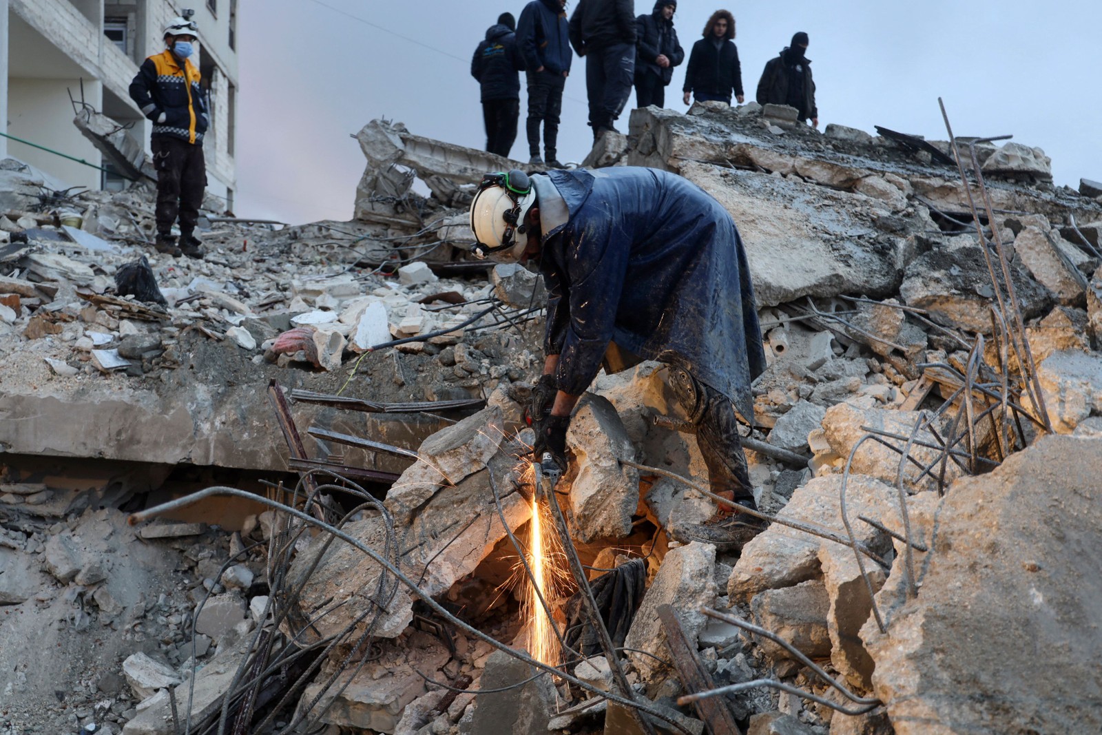Membros da defesa civil síria procuram vítimas sob os escombros após um terremoto na cidade de Zardana — Foto: Mohammed AL-RIFAI / AFP