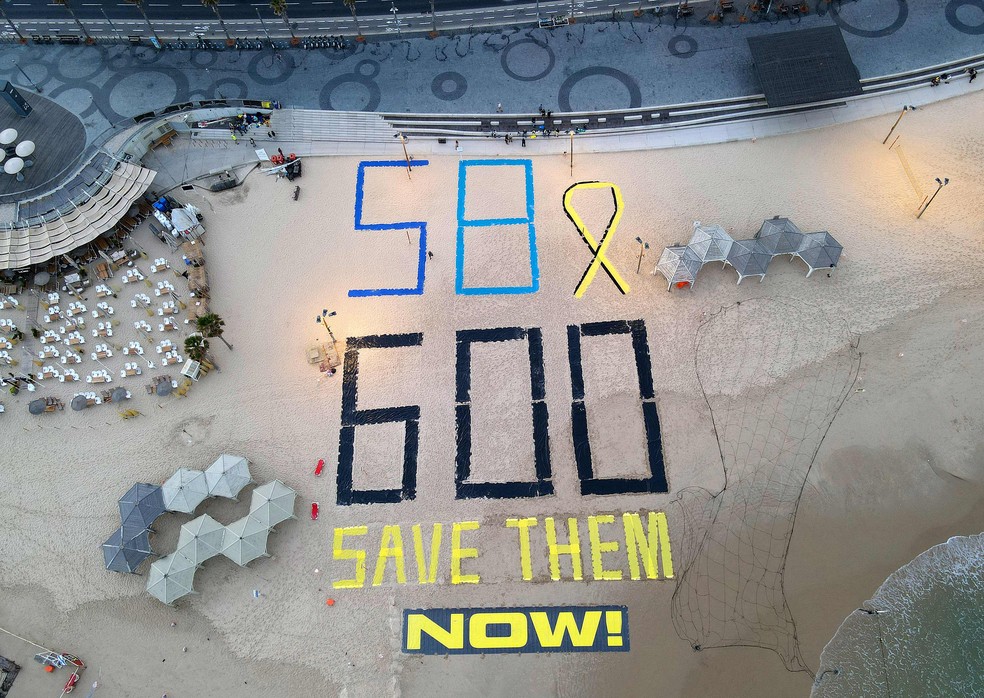 Manifestantes na orla de Tel Aviv fazem ato pedindo o retorno dos reféns israelenses ainda em Gaza, no dia em que a guerra completa 600 dias — Foto: Jack GUEZ / AFP