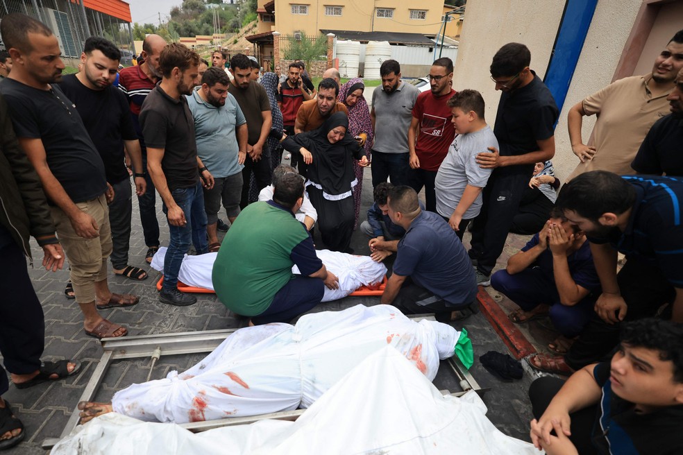 Parentes de vítimas da guerra entre Israel e Hamas encontram corpos de familiares — Foto: Mahmud Hams/AFP