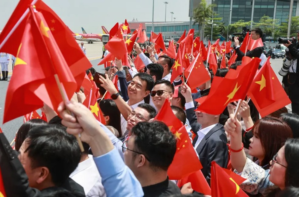 Xi foi recebido por vietnamitas acenando com bandeiras chinesas quando desembarcou na pista do aeroporto de Hanói pouco antes do meio-dia — Foto: Athit Perawongmetha/Pool/NYT