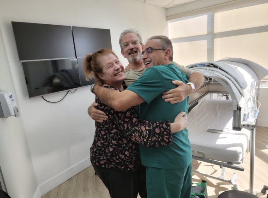 Da esquerda para a direita, Marianne Miller, esposa de Scott Miller, o paciente, e o médico Marc Abreu.  Foto: Divulgação/ btt Corp