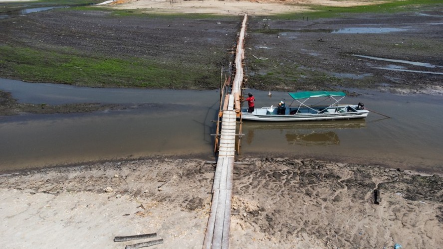 Barqueiro tem dificuldades de passar por baixo de ponte em curso d’água no Rio Negro, em Manaus