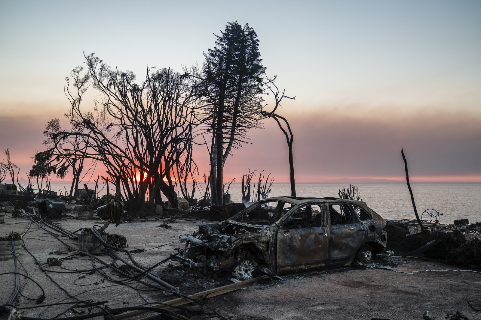 Linhas de serviços públicos derrubadas e um carro queimado pelo incêndio em Palisades ao longo da água ao nascer do sol em Malibu, Califórnia, na sexta-feira, 10 de janeiro de 2025 — Foto: Ariana Drehsler/The New York Times