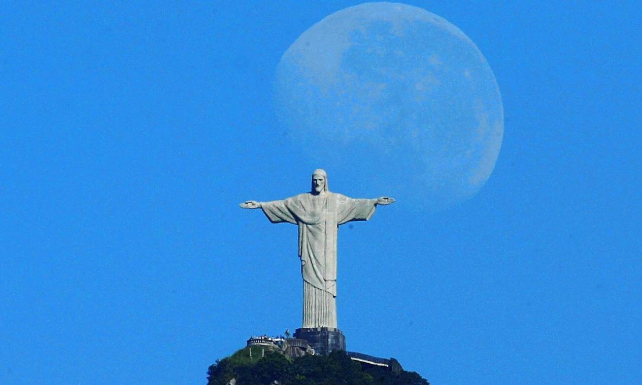 Lua nova é fotografada à luz do dia próxima ao Cristo  — Foto: Custódio Coimbra / Agência O Globo