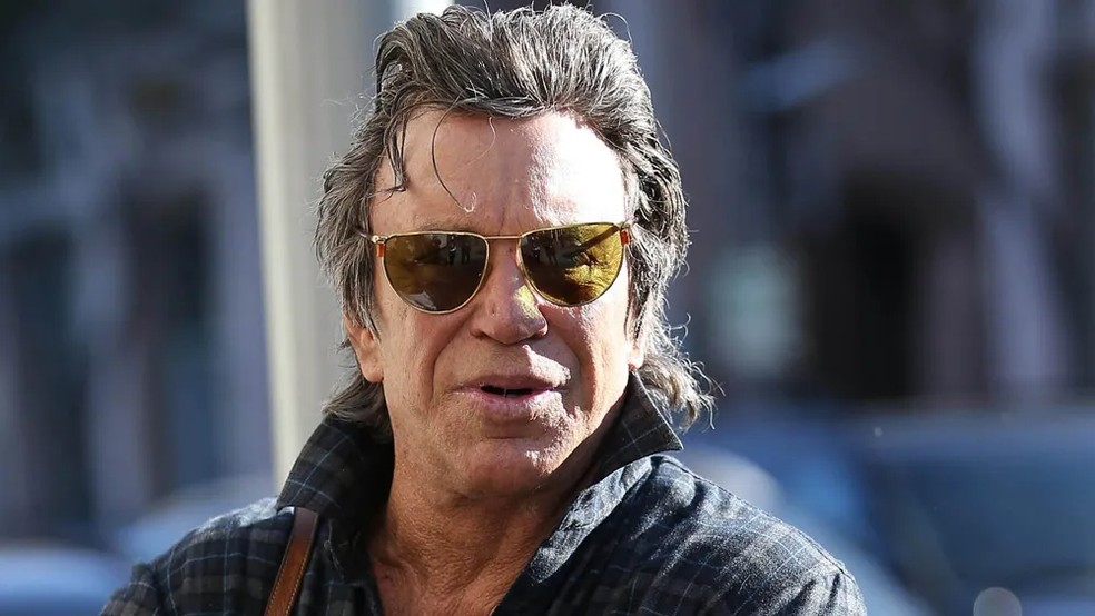 Mickey Rourke, que foi um dos rostos mais marcantes do cinema nos anos 1980, sofreu transformações faciais que, segundo ele próprio declarou em entrevistas, foram consequência de múltiplas cirurgias corretivas após ‘lesões no boxe’ — Foto: Reprodução