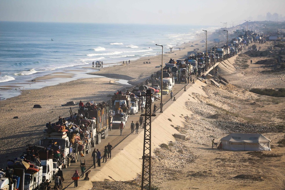 Palestinos deslocados seguem com seus pertences para o sul em uma estrada na área do campo de refugiados de Nuseirat, no centro da Faixa de Gaza — Foto: Eyad Baba/AFP