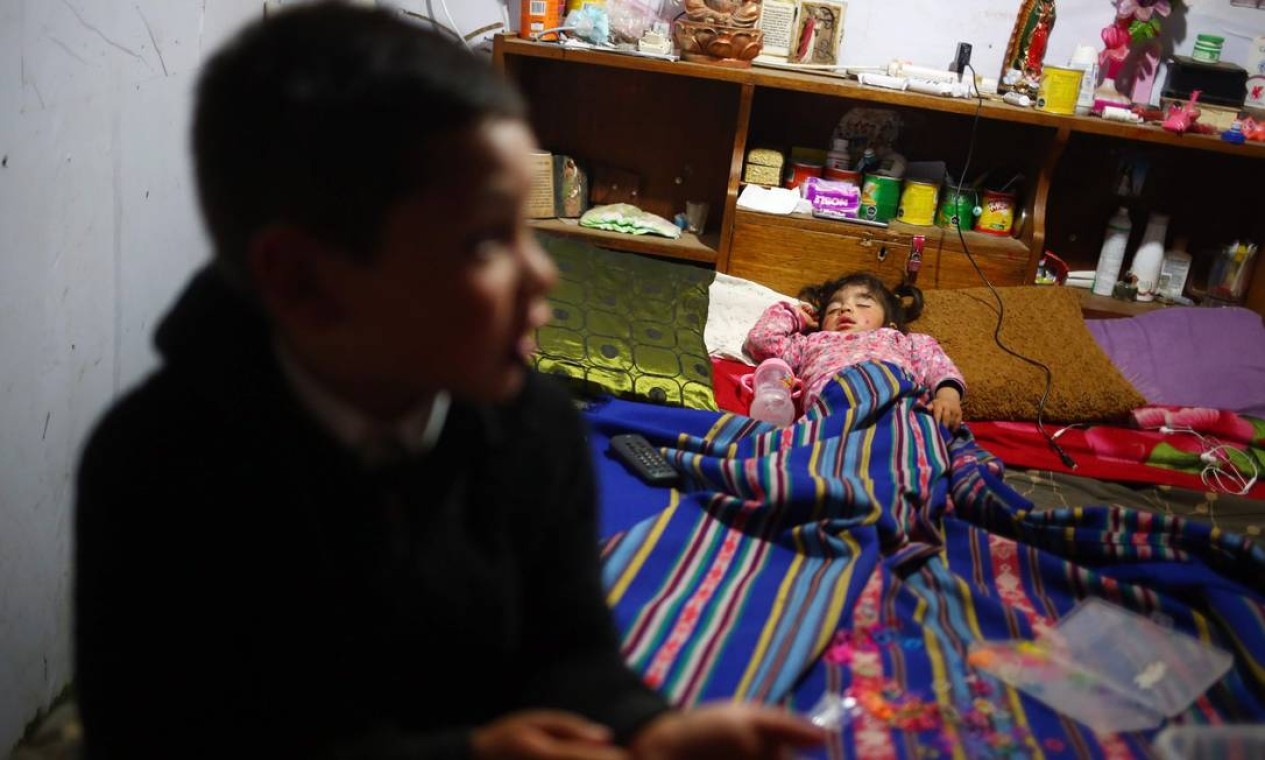 Netos da chilena Alejandria Arriaza descansam em sua casa, em Puchuncaví. Deyanira, de quase dois anos, sofre de uma doença pulmonar crônica que piora com a poluição — Foto: PABLO VERA / AFP