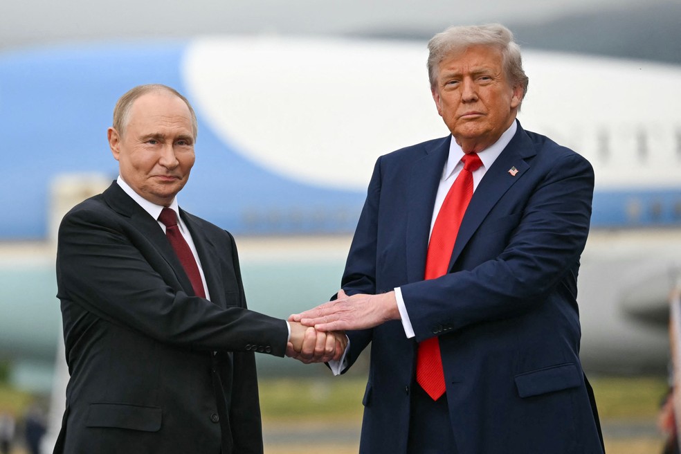 Presidentes da Rússia, Vladimir Putin (E), e dos EUA, Donald Trump, apertam as mãos antes de reunião em Anchorage, no Alasca — Foto: ANDREW CABALLERO-REYNOLDS / AFP