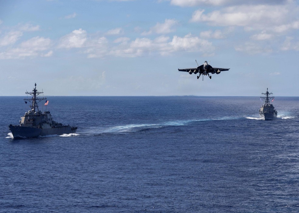 The destroyers USS Mahan and USS Bainbridge sail in formation as an F/A-18 Super Hornet approaches to land on the aircraft carrier Gerald Ford — Photo: Triniti Lersch/DoD/AFP