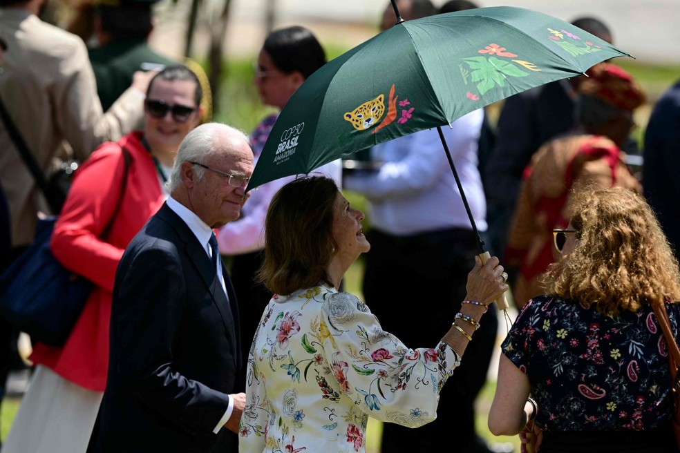 A rainha Silvia, da Suécia, protege-se do sol antes de participar da foto de família da COP30 ao lado do rei Carl XVI Gustaf — Foto: Pablo PORCIUNCULA / AFP