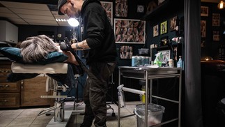 Darryl Veer, tatuador que fez dezenas de tatuagens cobrindo cicatrizes por quinze anos, trabalha em uma tatuagem artística em torno das cicatrizes de mastectomia — Foto: Simon Wohlfahrt/AFP