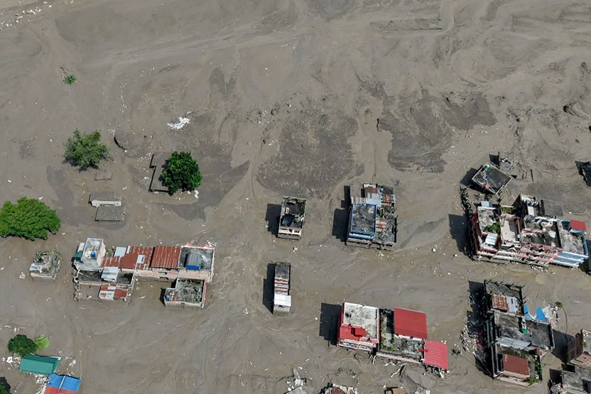 Casas ficam parcialmente submersas em água barrenta ao longo da margem de um rio após inundações — Foto: Prabin RANABHAT / AFP