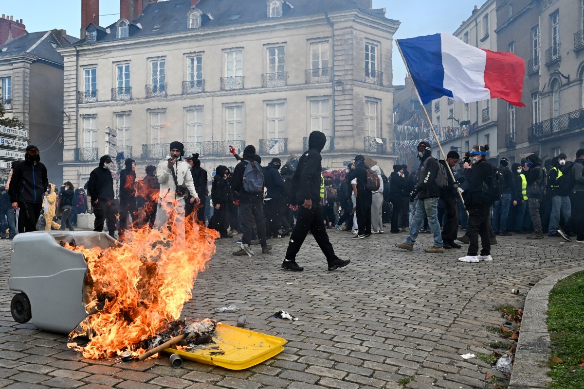 Em Nantes, no oeste da França, manifestantes reunidos no protesto nacional contra o alto custo de vida no país; Um deles segura a bandeira francesa — Foto: SEBASTIEN SALOM-GOMIS / AFP