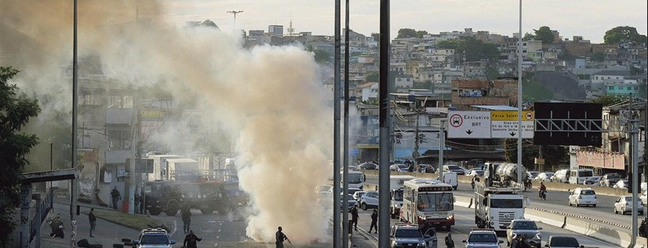 A car set on fire by drug traffickers closes the side lane of Avenida Brasil, near Cidade Alta: bandits also set up roadblocks throughout the favela to prevent the advance of police forces — Photo: Domingos Peixoto / Agência O Globo