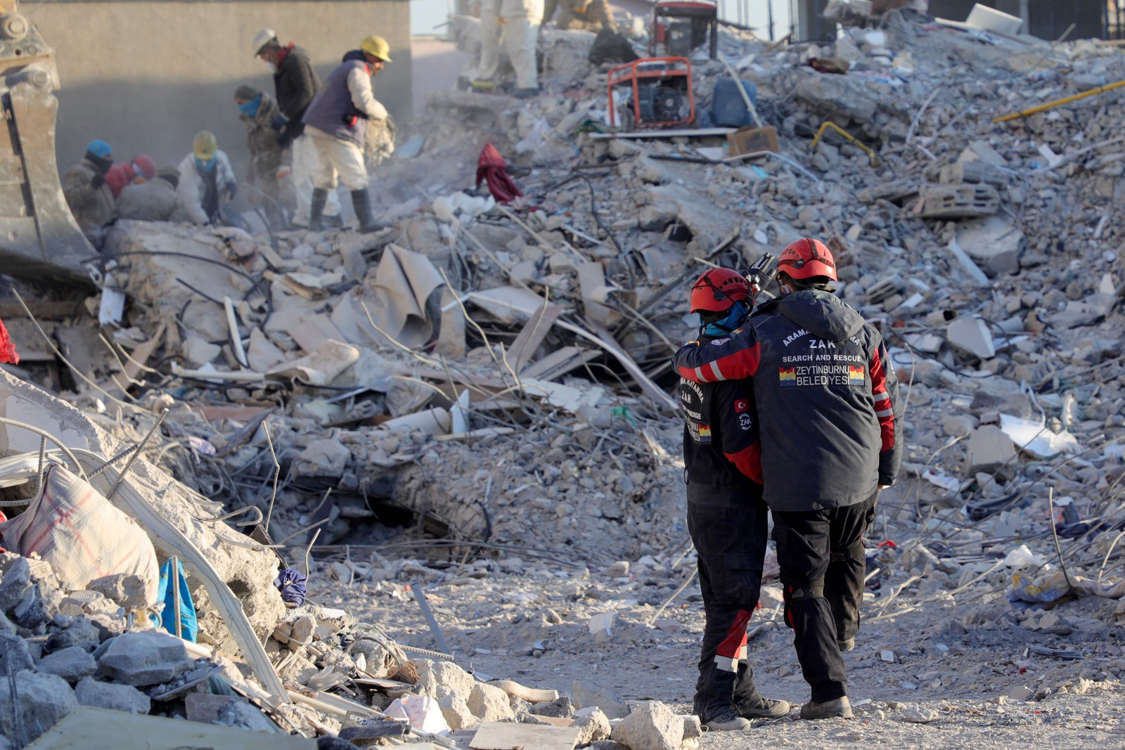 Agentes de resgate se consolam com os escombros de edifícios desabados em Nurdagi, perto de Gaziantep, Turquia — Foto: ZEIN AL RIFAI/AFP