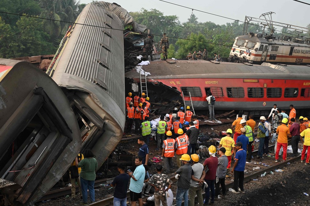 Equipes de resgate se reúnem em torno dos trens danificados no local da colisão perto de Balasore, a cerca de 200 km da capital do estado Bhubaneswar — Foto: Dibyangshu SARKAR / AFP