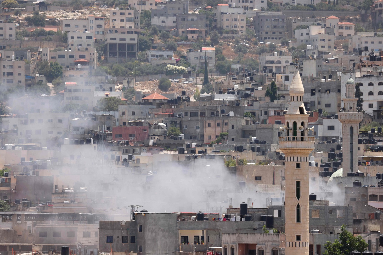 Fumaça sobe entre edifícios durante ataque militar israelense na cidade de Jenin, na Cisjordânia, em 3 de julho de 2023 — Foto: RONALDO SCHEMIDT / AFP